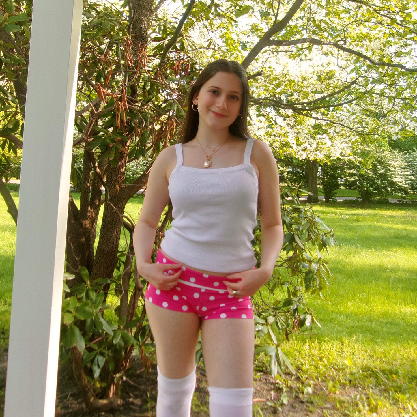 Model wearing micro pink and white polka dot shorts with a fold-over waistband, standing straight.