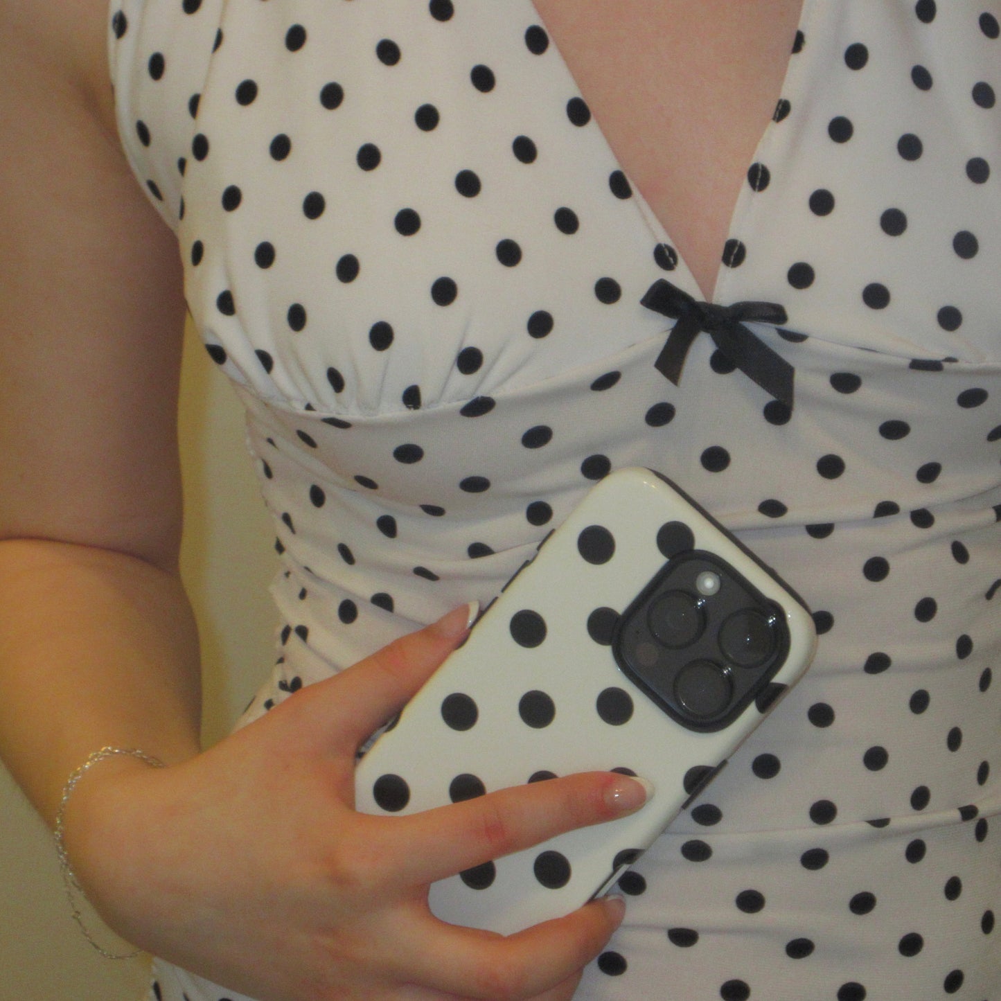Person wearing a polka dot top holding a phone with a matching case.