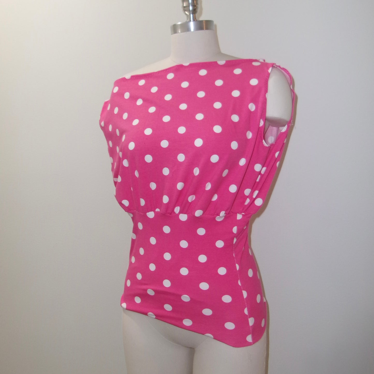 Pink polka dot top on a mannequin against a plain background