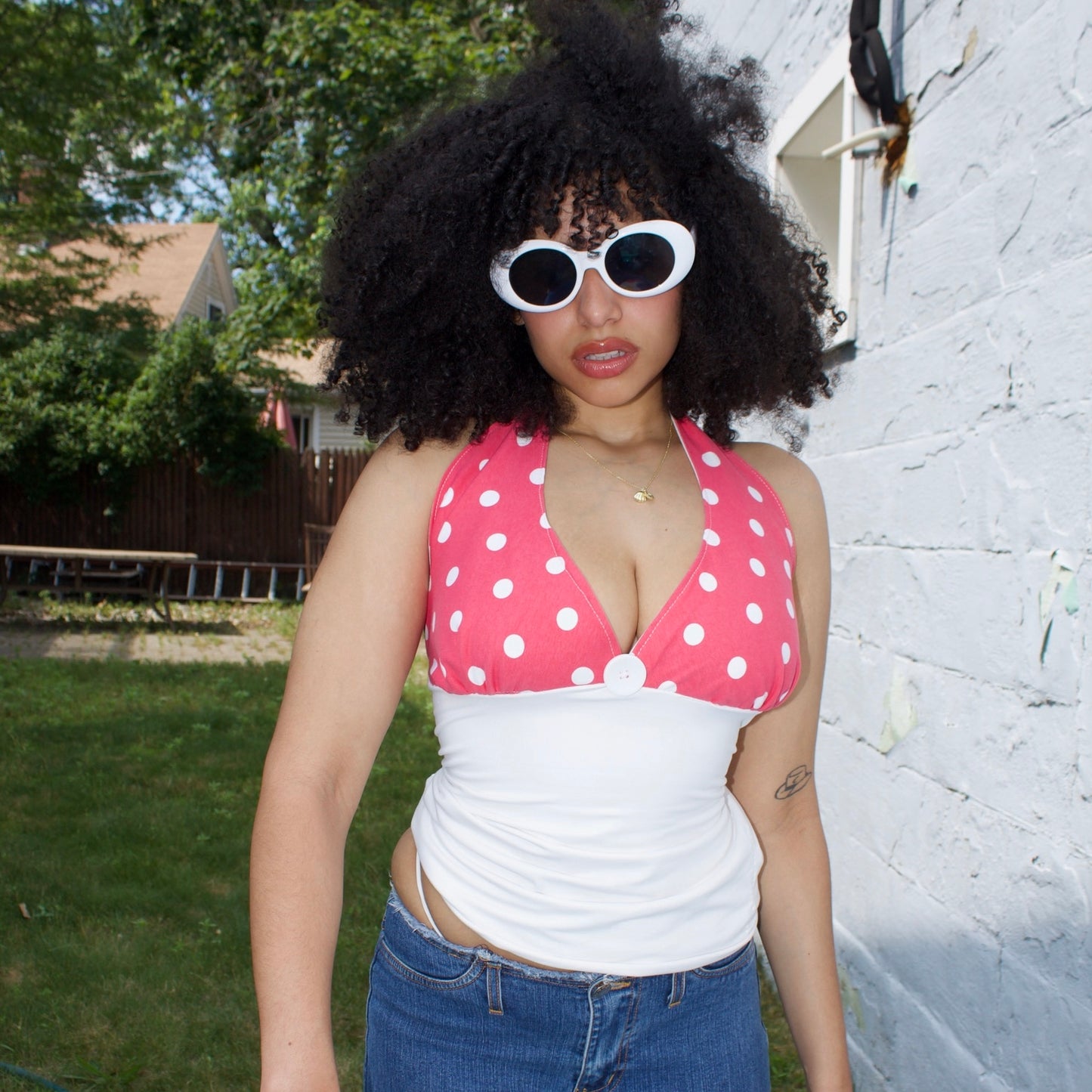 Person wearing a pink polka dot top, standing outdoors.