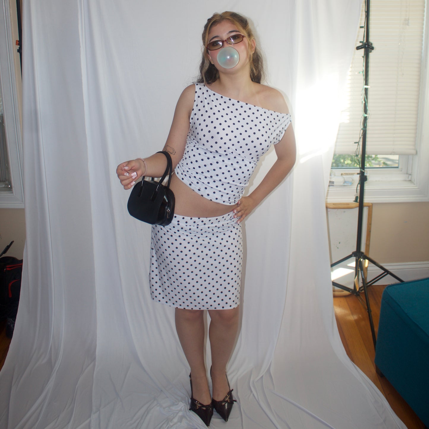 Woman in a polka dot dress posing in front of a white backdrop