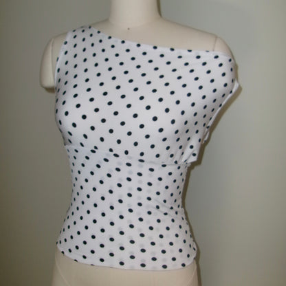 White sleeveless top with black polka dots on a mannequin against a plain background