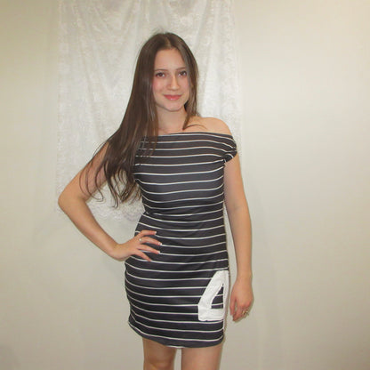 Woman wearing a black and white striped dress with a number on a plain background