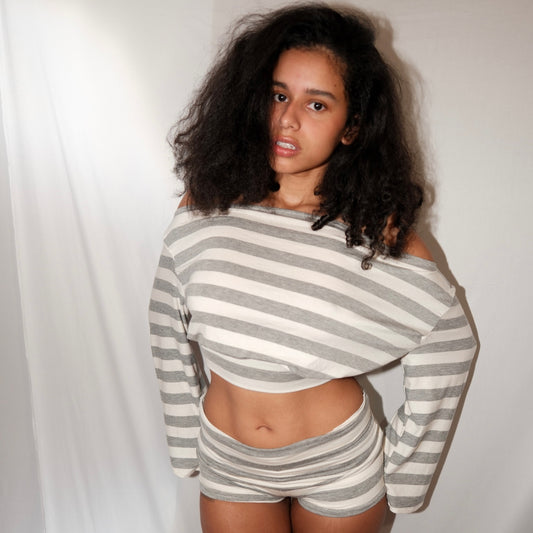 Woman wearing a gray and white striped outfit against a plain background