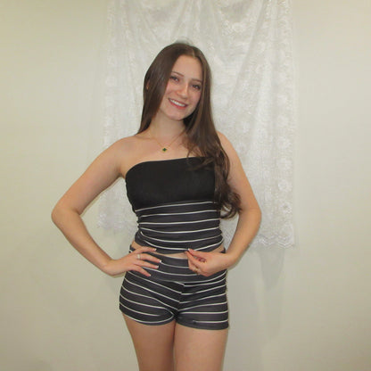 Woman wearing a black strapless top and striped shorts against a neutral background
