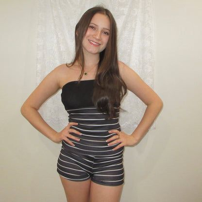 Woman wearing a black and white striped outfit against a plain background