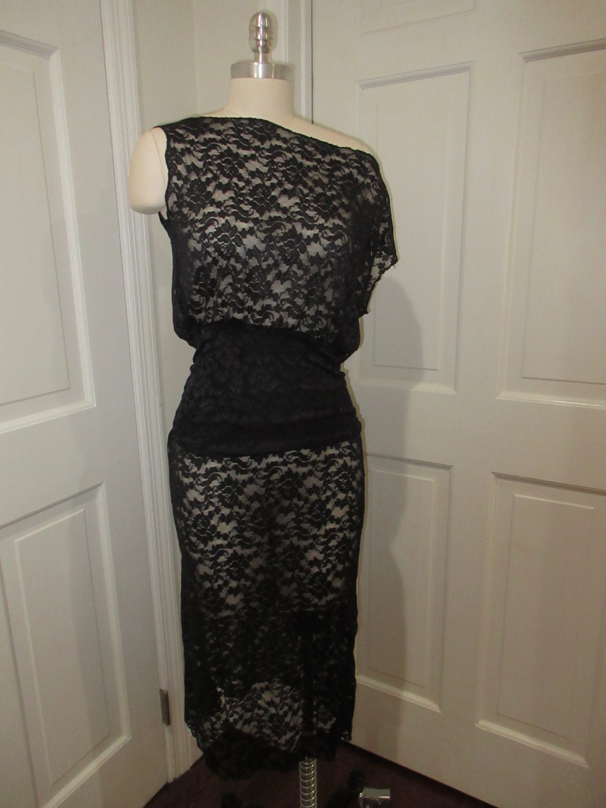 Black lace dress on a mannequin against a white door background