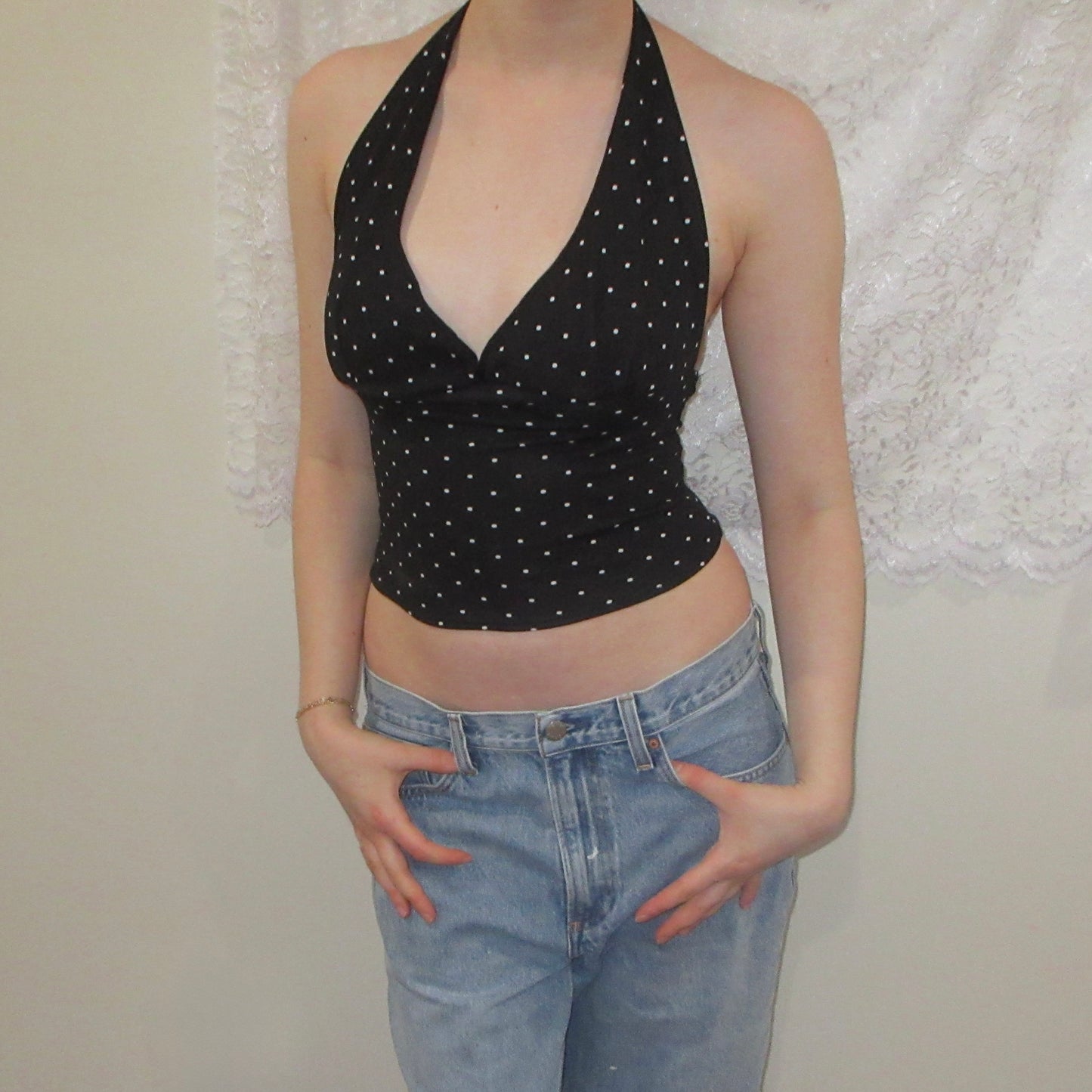 Black polka dot halter top and blue jeans against a neutral background