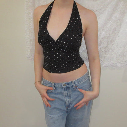 Black polka dot halter top and blue jeans against a neutral background