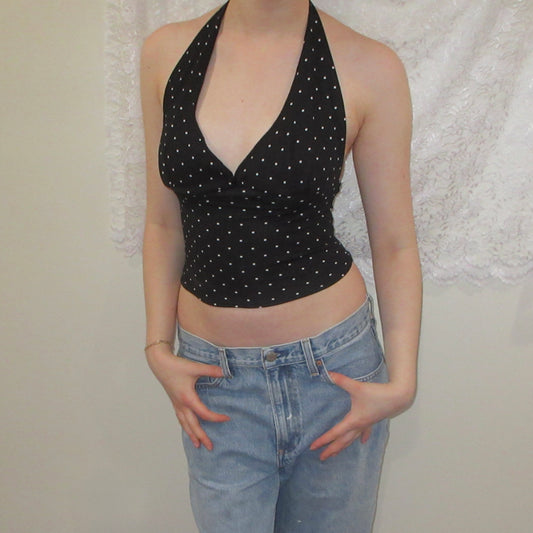 Black polka dot halter top and blue jeans against a neutral background