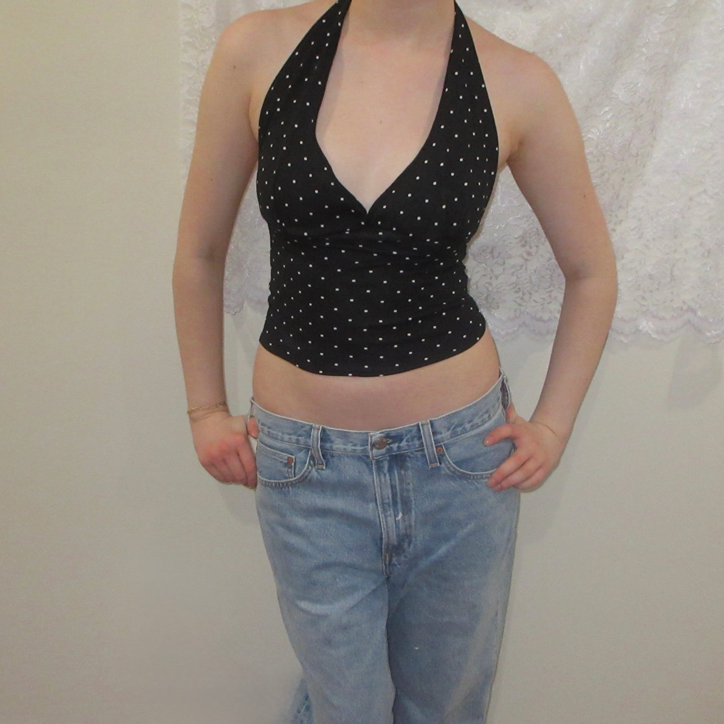 Black polka dot halter top and blue jeans against a white background