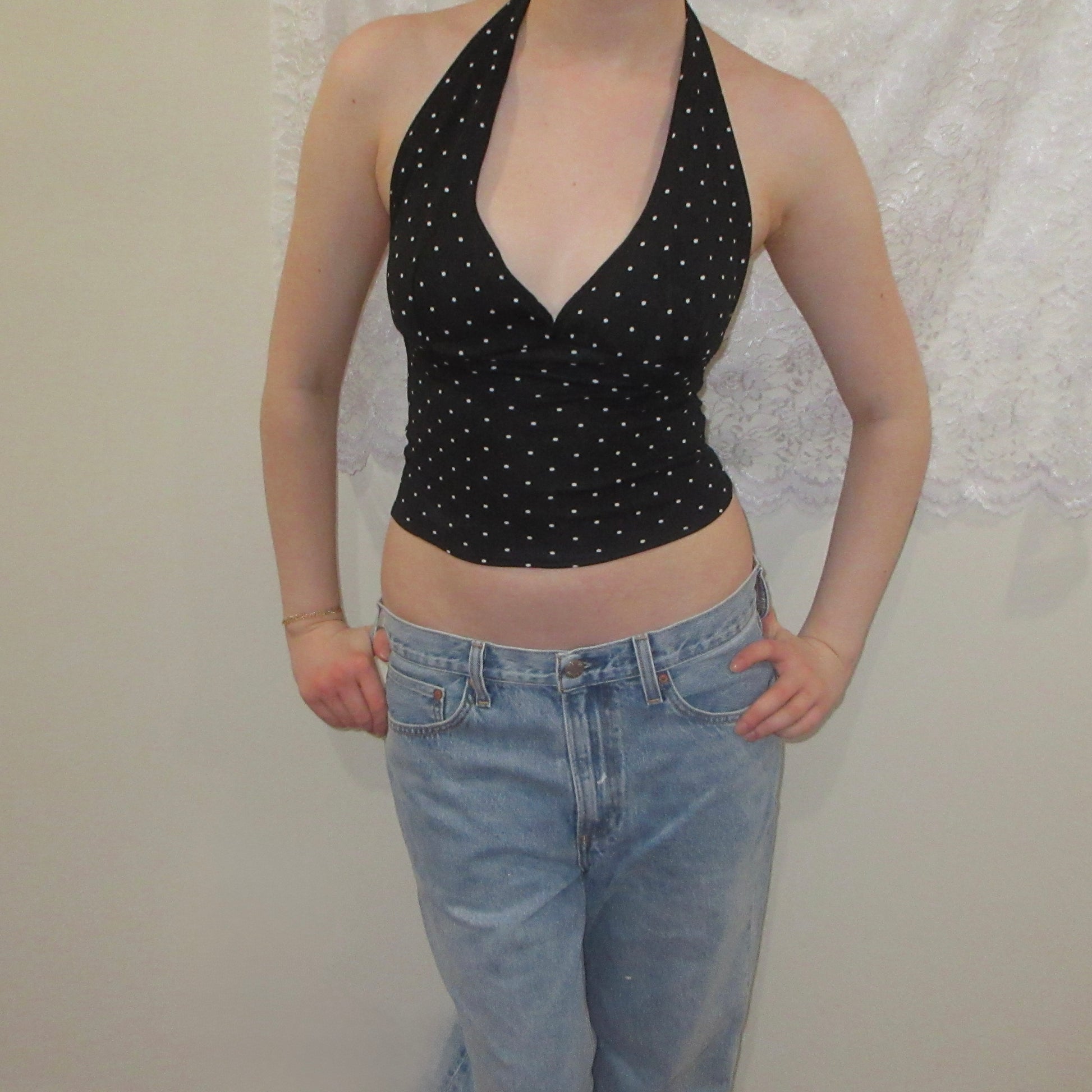 Black polka dot halter top and blue jeans against a white background