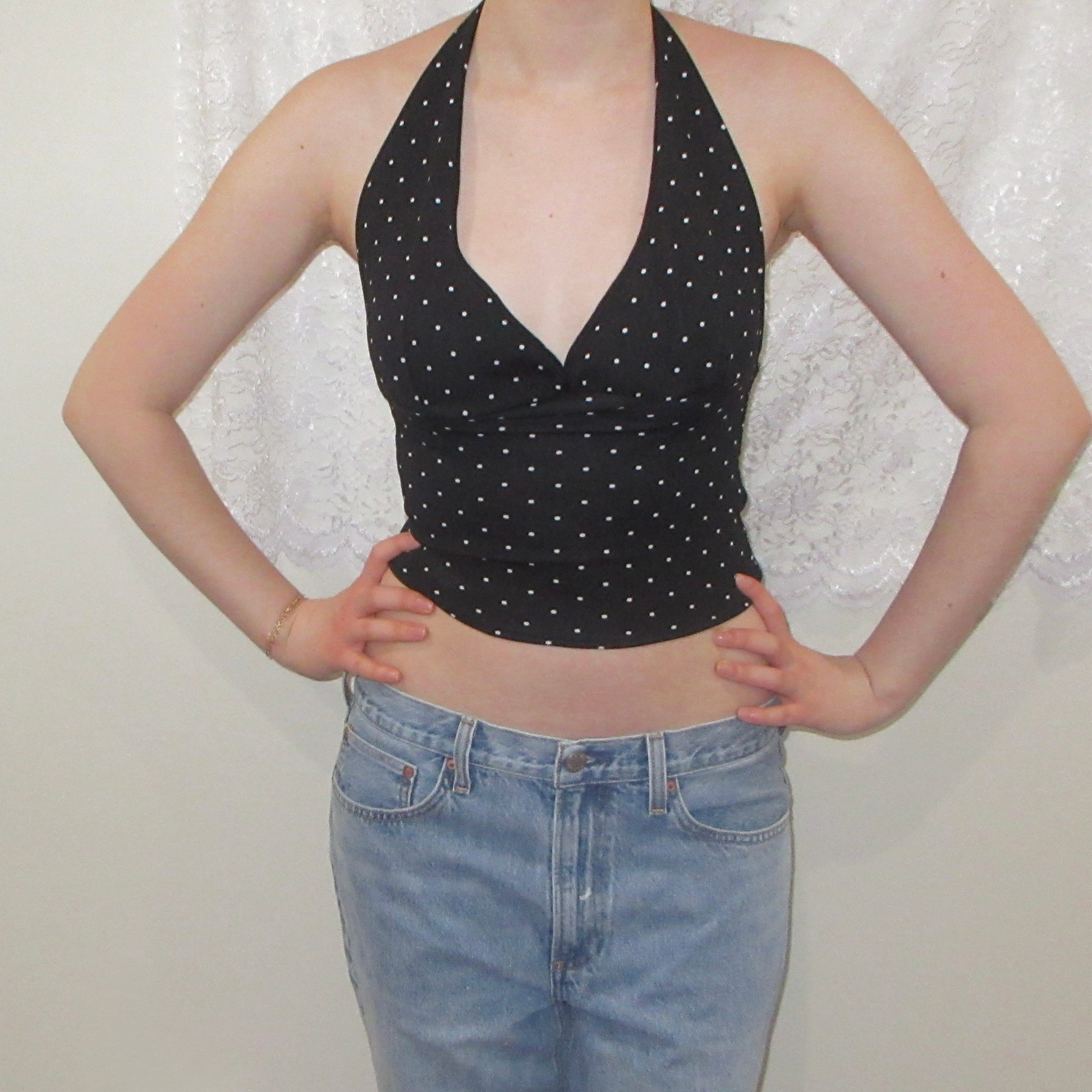 Black polka dot halter top and blue jeans against a white background