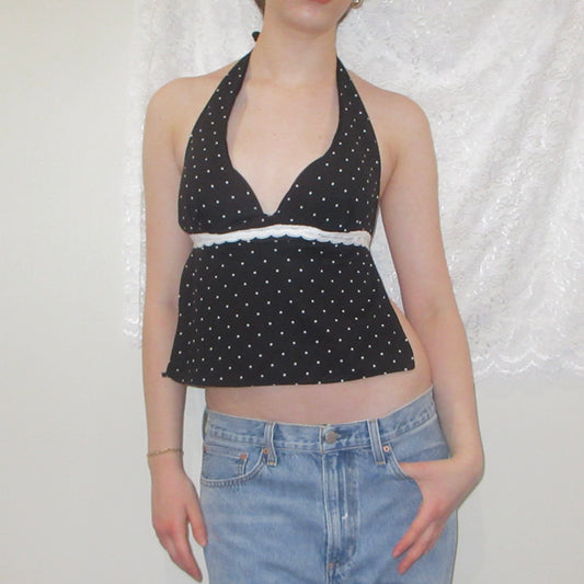 Black polka dot halter top and blue jeans against a white background