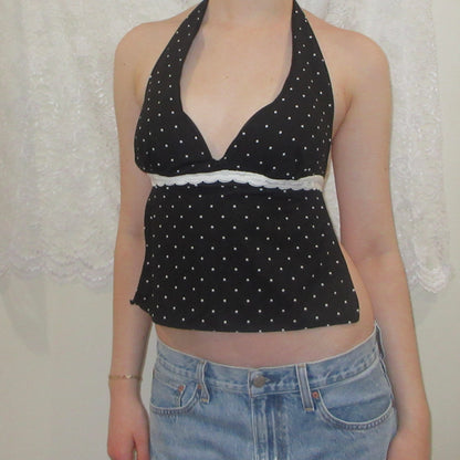Black polka dot halter top worn by a person with a white lace curtain background