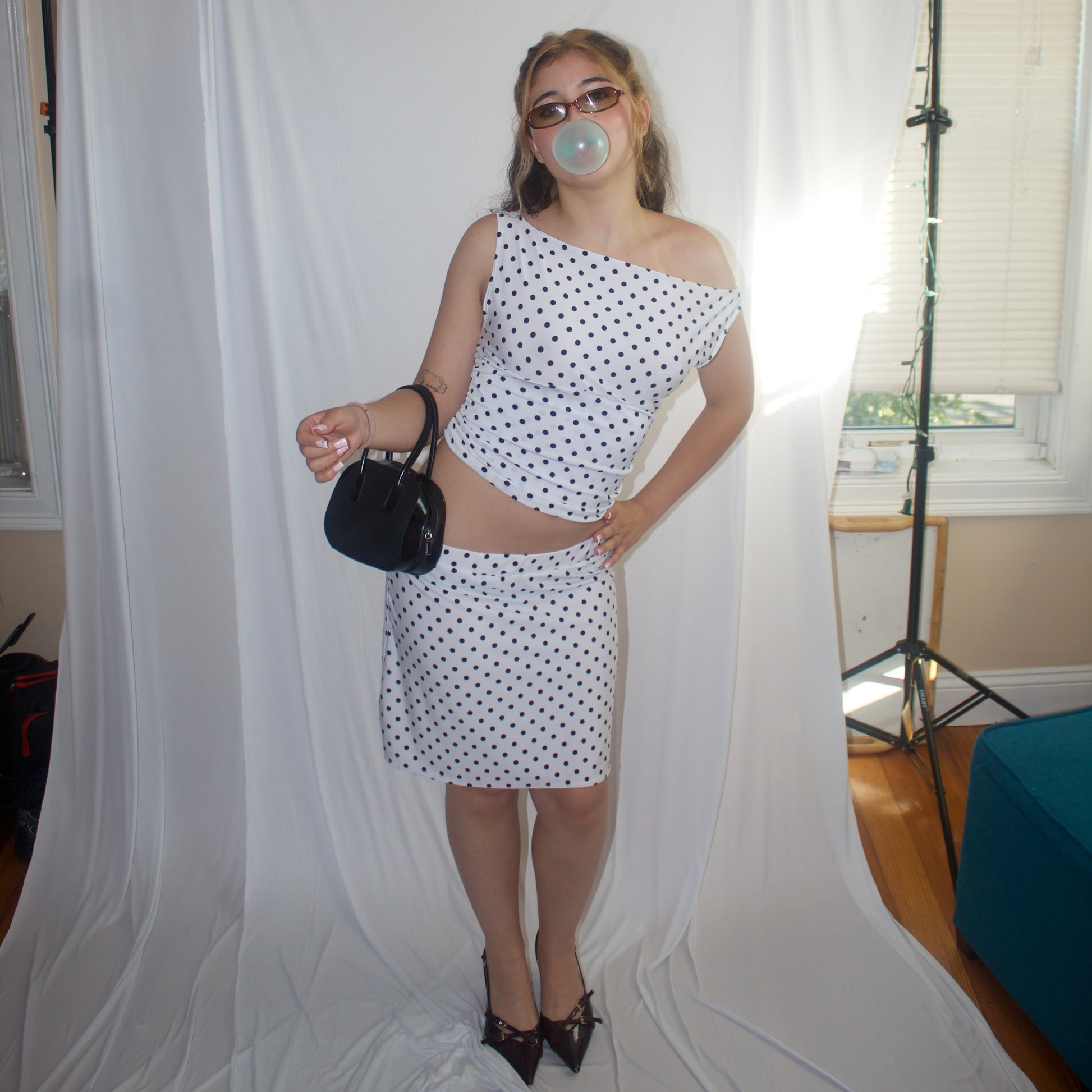 Woman in a polka dot dress posing in front of a white backdrop