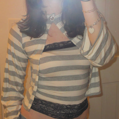 Person wearing a striped shirt over a black lace top with a neutral background