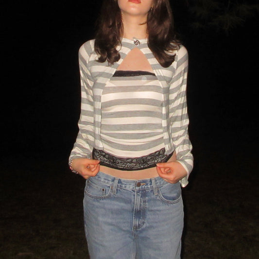 Person wearing a striped cardigan and jeans against a dark background