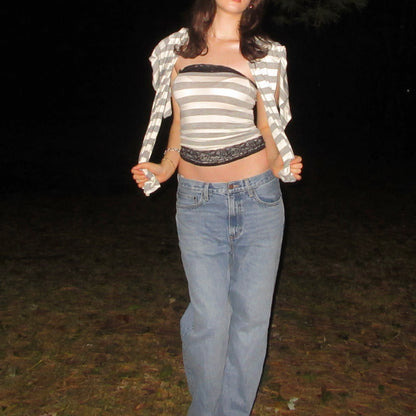 Person wearing a striped top and jeans in a dark outdoor setting
