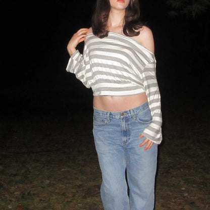 Person wearing a striped sweater and jeans against a dark background